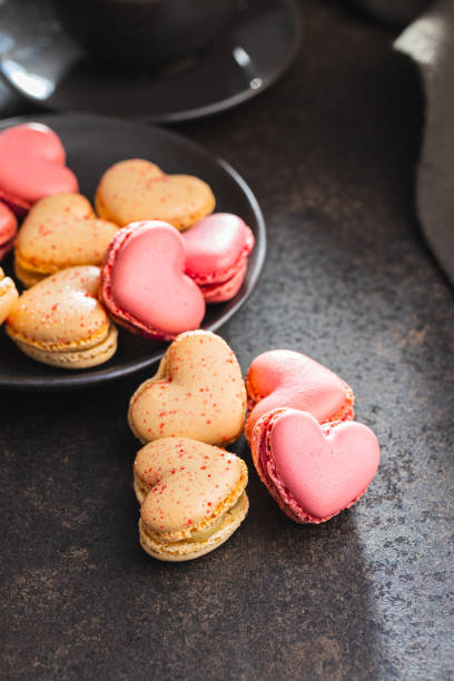 istock Heart shaped Sweet macarons on black table. 1400060497