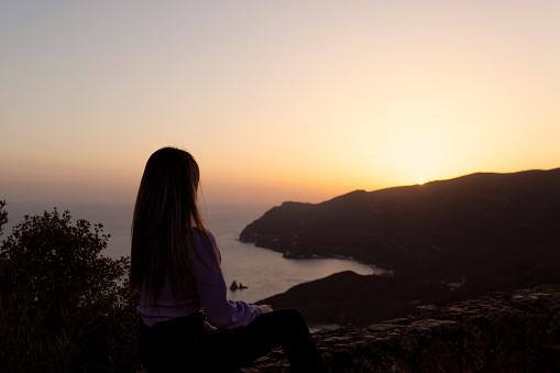Young woman near a cliff in Arrábida Nature park enjoys the sunset