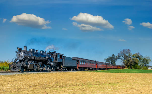 View of an Antique Steam Train Locomotive Approaching Thru Trees Ronks, Pennsylvania, October 2019 - A View of an Antique Steam Locomotive Approaching and Coaches Thru Trees on a Sunny Day road going steam engine stock pictures, royalty-free photos & images