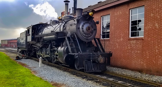 A Restored Steam Engine Getting Ready for Service, Blowing Smoke and Steam on a Cloudy Summer Day