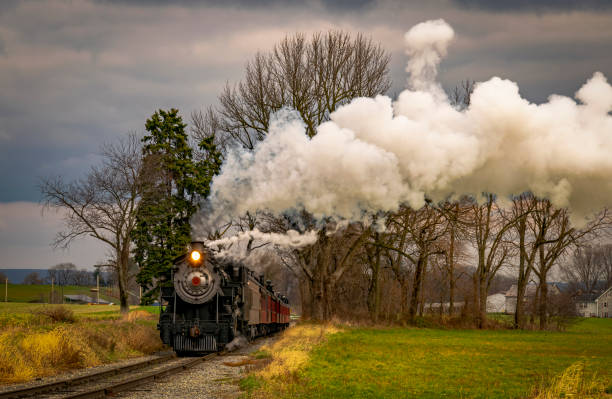 istock View of an Antique Freight Steam Train Blowing Smoke Approaching Thru Trees 1400062127