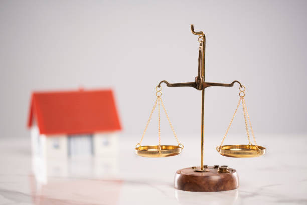 Scales of justice and a model house are on the white table stock photo