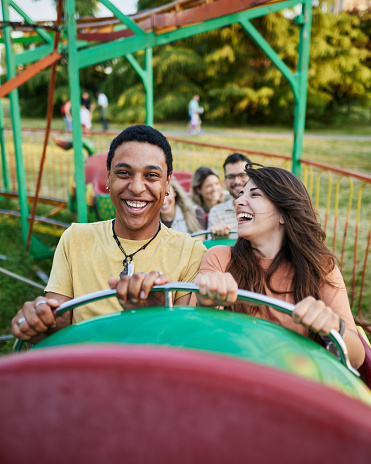 Young happy couple having fun on rollercoaster at amusement park.