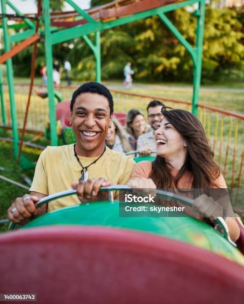 Happy Couple Having Fun While Riding On Rollercoaster At Amusement Park Stock Photo - Download Image Now