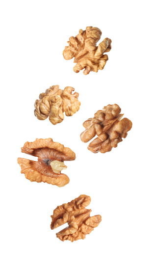 Halves of walnuts falling on white background