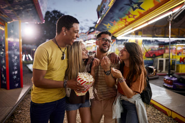 istock Happy couples talking while eating popcorn at amusement park. 1400065059