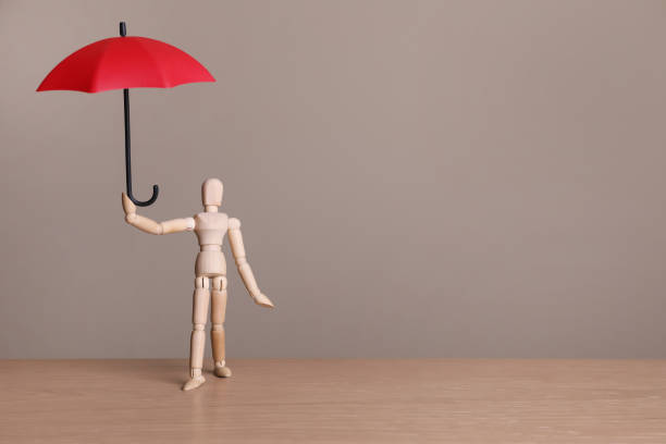 istock Mannequin holding small umbrella on wooden table. Space for text 1400065120