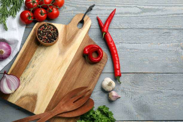 istock Cutting board and vegetables on grey wooden table, flat lay with space for text. Cooking utensils 1400065155