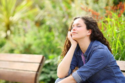 Woman resting with closed eyes sitting in a park