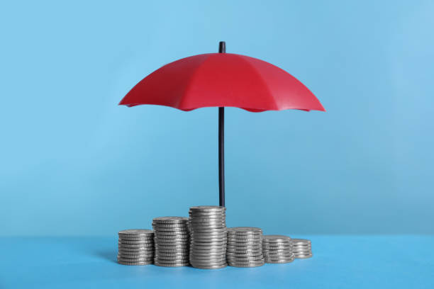 istock Small umbrella and coins on light blue background 1400065589
