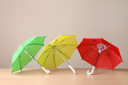 Small color umbrellas on wooden table against beige background