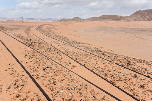 Old train rails almost completely covered with desert sand in Wadi Rum, Jordan.