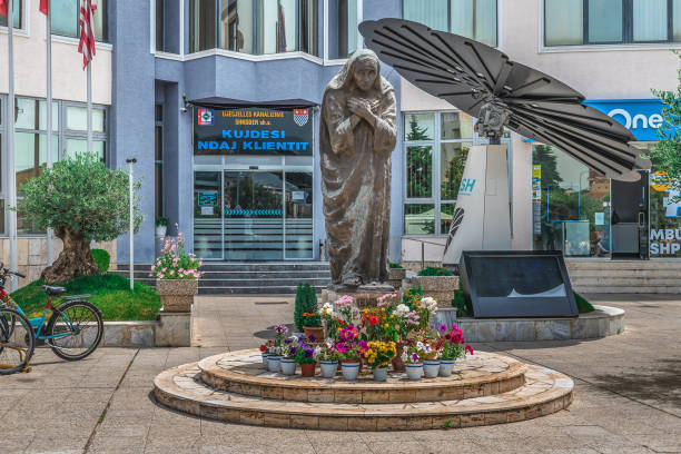 Shkoder, Albania - June 21, 2021: Statue of Mother Teresa on Rruga Kole Idromeno Street in Shkoder. Many colorful flowers near the pedestal of the monument to the famous catholic nun