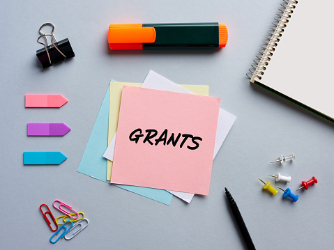 La palabra grants escrita en un papel de nota en el escritorio de la oficina empresarial. Financiación o apoyo financiero en educación o negocios. photo