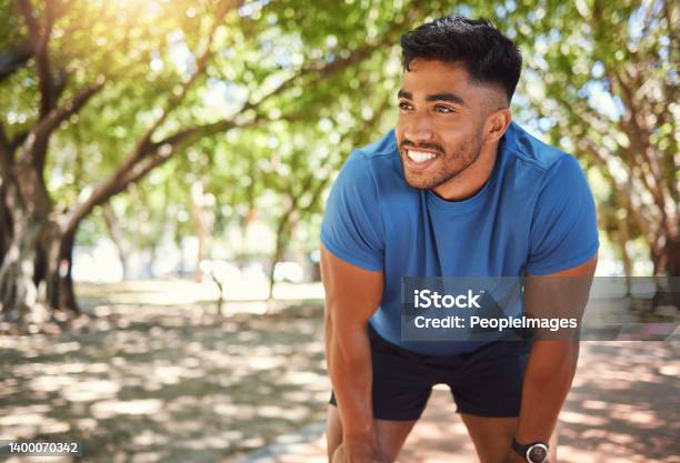 Happy Athletic Mixed Race Man Smiling While Standing With His Hands On His Knees In A Park Hispanic Male Resting After His Run Fit Man Pleased With His Performance While Exercising Outdoors Stock Photo - Download Image Now