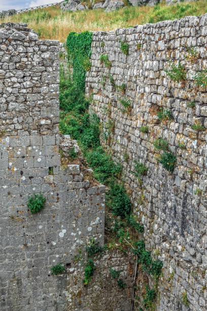 istock Ancient stone wall overgrown with grass in Rozafa Castle in Albania, vertical 1400070775