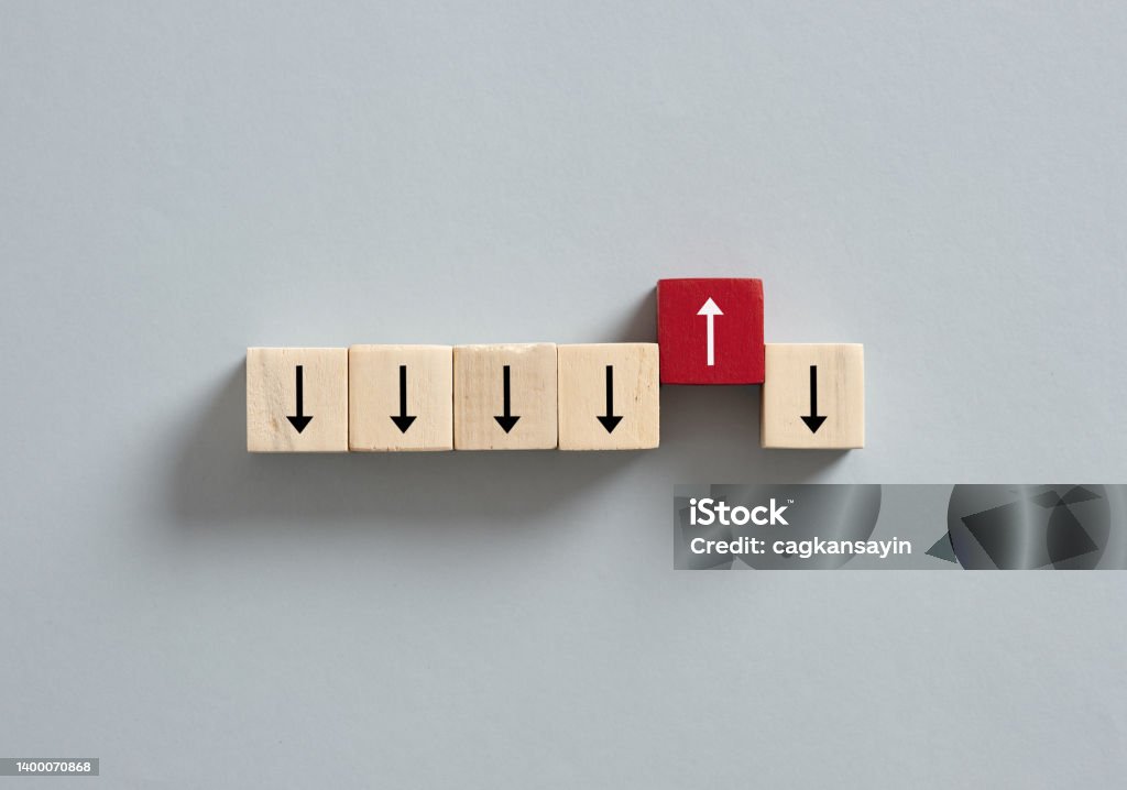Red wooden cube with the up arrow among the cubes with down arrows. Opportunity Stock Photo