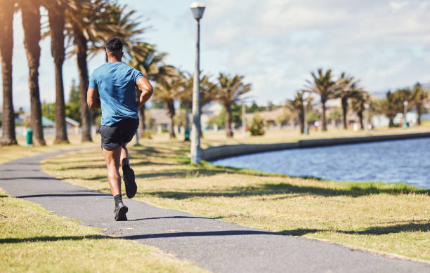 istock Rearview active fit male doing running exercises alone in a park outside on a sunny day. Muscular legs of a mixed race male runner wearing sportswear. Speed, endurance, stamina and strength training 1400071149