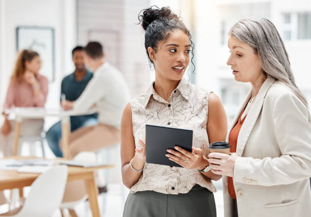 istock Businesspeople using a digital tablet together at work. Serious mixed race and caucasian business professionals talking while planning and working on a digital tablet together in an office 1400071213