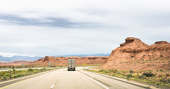 Rear view of a silver insulated refrigerated truck on a journey through an arid landscape.