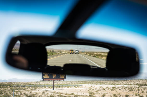 A view in a car's rear-view mirror of two large trucks, following on a remote rural highway in Nevada.