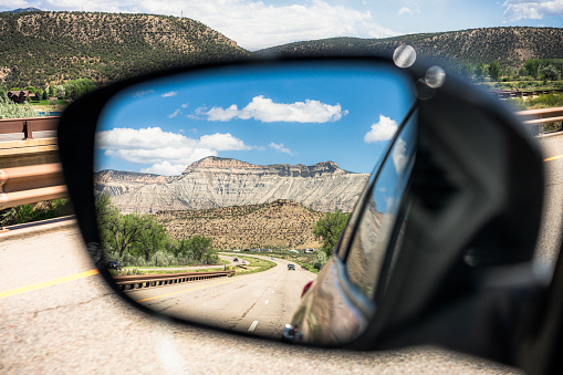 A driver's point of view, checking for vehicles in the car's side view mirror during an interstate freeway journey.