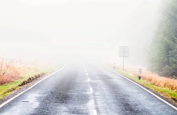 brouillard enveloppant une route rurale - asphalt two lane highway natural phenomenon fog photos et images de collection