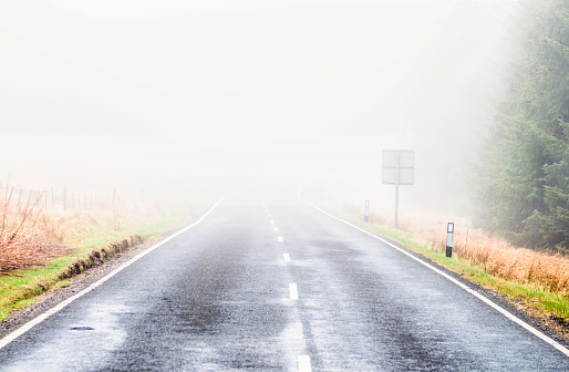 Severely reduced visibility on a country road in the UK due to thick fog.