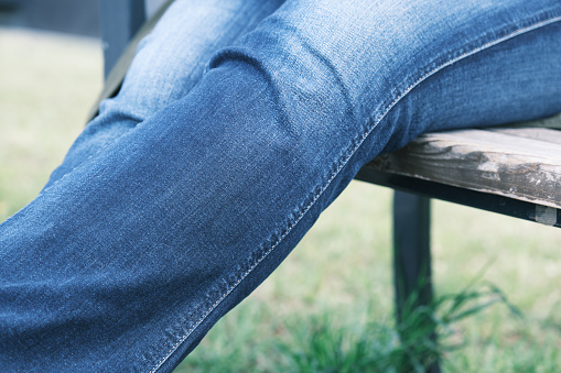 Woman is sitting on the bench in residential district. Fragment shot - legs