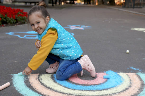 istock Happy child drawing rainbow with chalk on asphalt 1400072122