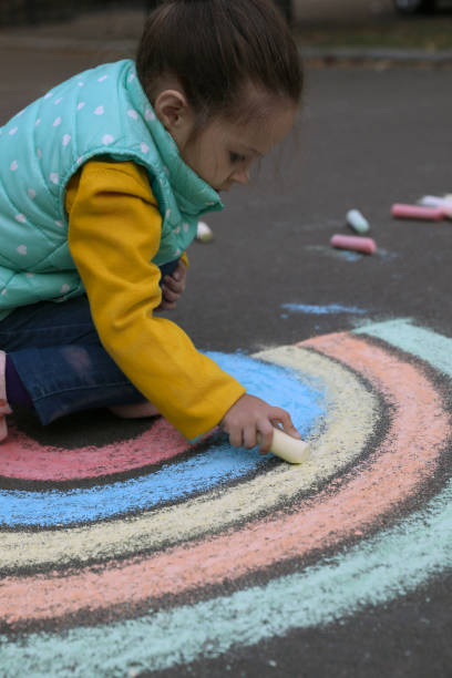 istock Child drawing rainbow with chalk on asphalt 1400072177