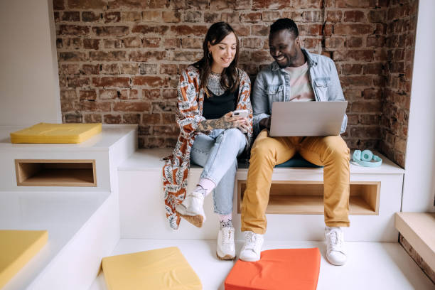 Two casually clothed colleagues using laptop on a job break