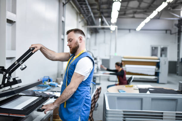 istock Bearded Male Worker Using Cloth Printer In Textile Factory 1400073785