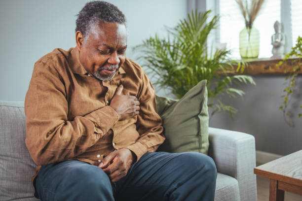 istock African senior man sitting on sofa at home with sickness. 1400074999