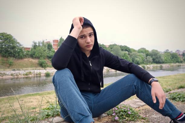 Boy with black hooide sitting alone depresed