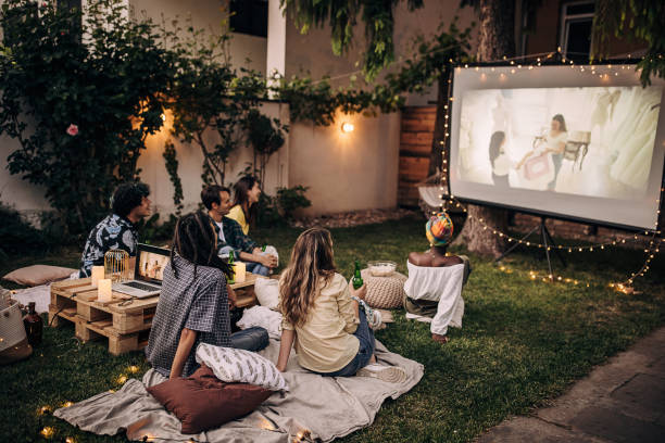 amigos viendo películas en el proyector de video en el jardín del patio trasero - equipo de proyección fotografías e imágenes de stock