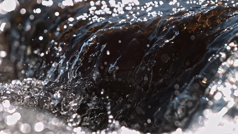 SUPER SLO MO Close-up Water flows down a brown stone,small waterfall in a river,view from the side