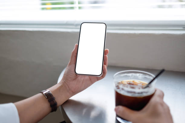 istock Mockup image of a woman holding mobile phone with blank desktop screen while drinking coffee 1400078191