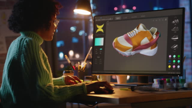Black Teen Woman Creating and Rendering 3D Model of Unique Sneaker at Personal Computer During Work at Evening. Freelance and Millennial People Concept