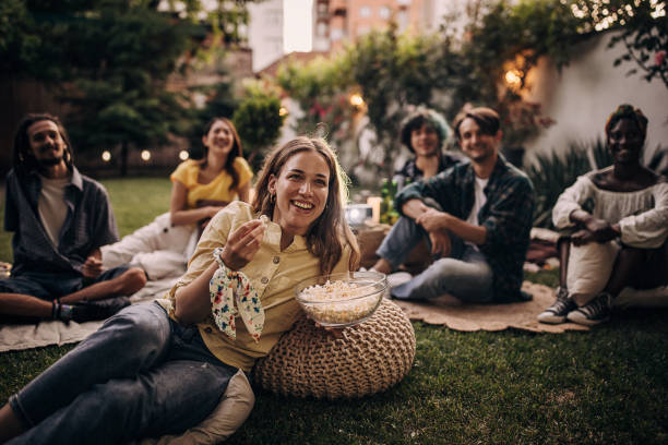 Friends watching movie on the video projector in the backyard garden stock photo