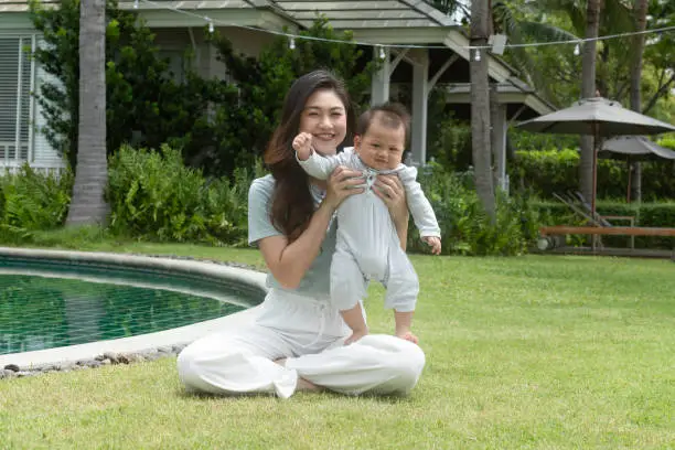 Happy Asian mom holding her newborn baby smile and spending time for good moment together. Adorable little baby boy having fun and cheerful with love from mother.Mother day concept