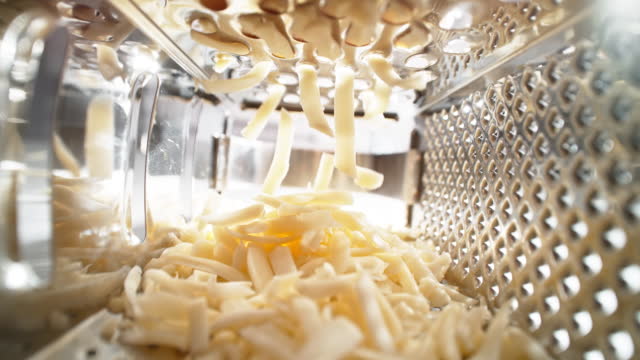 Grated Cheese Strips Falling into the Cheese Grater - View from Inside of the Kitchen Utensil