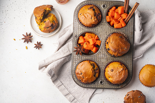 Homemade spicy pumpkin muffins or cupcakes with chocolate on a metal rack, top view. Autumn dessert. Selective focus