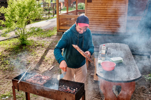 istock Middle aged man cooking chicken meat on barbecue grill in backyard. 1400083217
