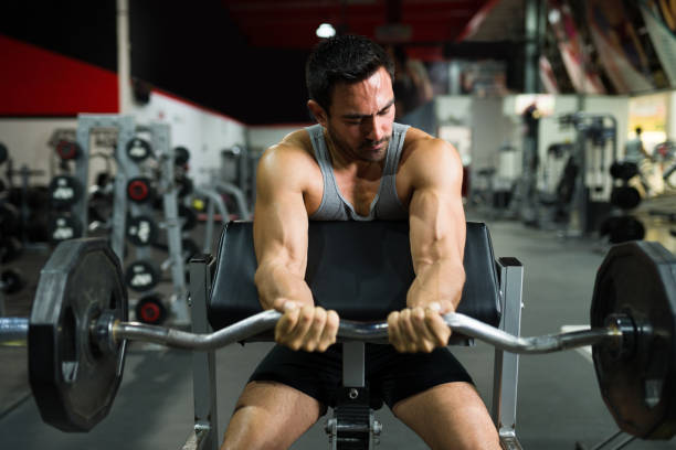istock Fit trainer doing biceps and lifting a barbell 1400083415