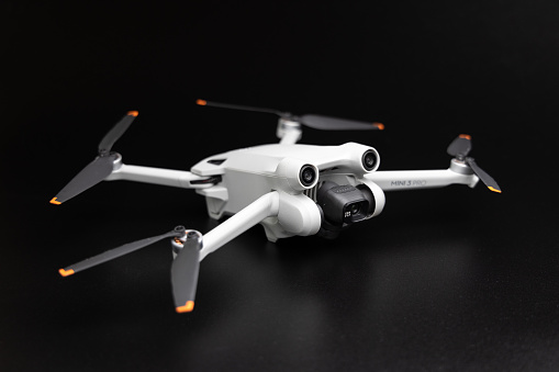 Germany – May 27, 2022: Studio shot of the new DJI Mini 3 Pro drone on a dark background. Front/side view of the standing drone.