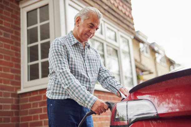 istock Mature Man Attaching Charging Cable To Environmentally Friendly Zero Emission Electric Car At Home 1400086147