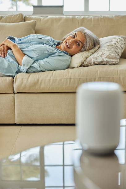istock Mature Woman Lying On Sofa Asking Digital Assistant Or Smart Speaker Question 1400087244