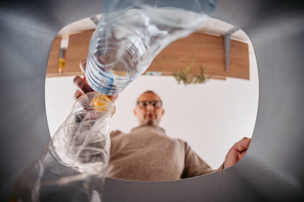 Young Man Putting Plastic Bottles In The Recycling Bin