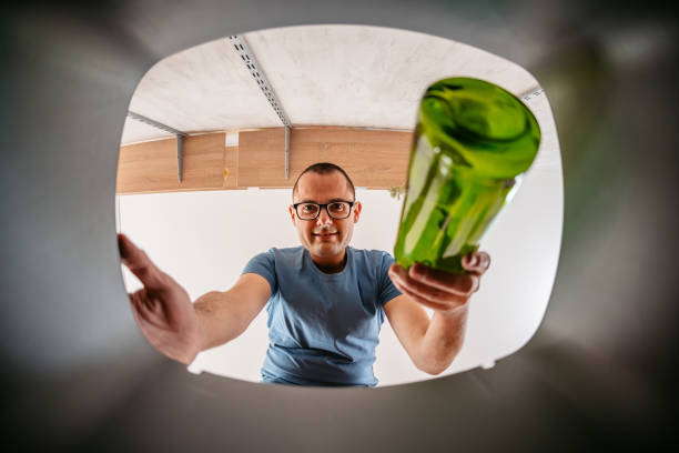 istock Young Man Putting Glass Bottle In The Recycling Bin 1400087940
